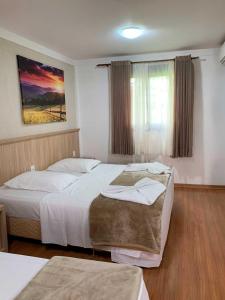 a bedroom with two beds and a painting on the wall at Hotel San Lucas in Gramado +49 photos