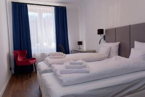 a hotel room with two beds and a red chair at Apartament e-Space in Rzeszów