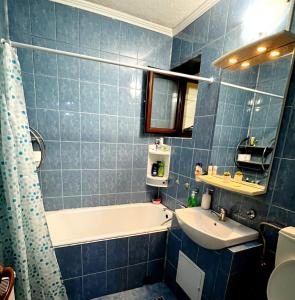 baño de azulejos azules con bañera y lavamanos en Apartament Modern Family, en Târgu Ocna