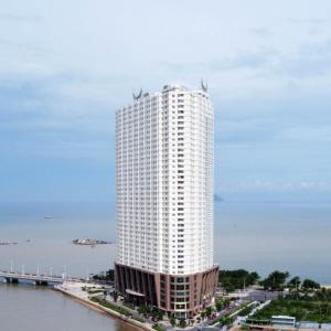 a tall white building next to the water at Phi Yen Muong Thanh 04 Apartment in Nha Trang