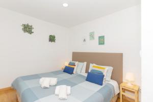 a white bedroom with a blue bed with pillows at Sunny Oporto, Douro Apartments in Porto