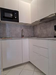 una cucina con armadietti bianchi e forno a microonde di Apartmani Beba a Trogir