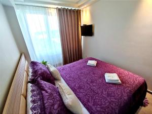 a bedroom with a purple bed with two towels on it at 2BR+living downtown Chișinău in Chişinău