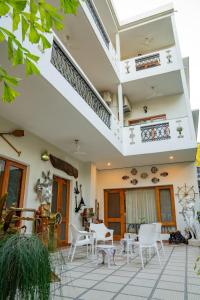 une terrasse avec des chaises et des tables blanches dans une maison dans l'établissement Anchorage 42, à Chandigarh