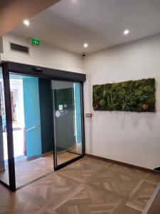 una hall con una porta aperta e una pianta sul muro di Hotel Le M a Marsiglia