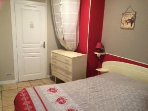 a bedroom with a bed and a red wall at Le Mont Dore Résidence Cottage rez de chausse in Le Mont-Dore