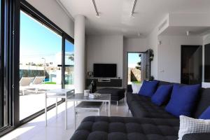 sala de estar con sofá negro y almohadas azules en La casa del sol villa de luxe, en Ciudad Quesada