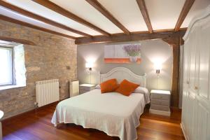 1 dormitorio con 1 cama blanca y 2 almohadas de color naranja en Casa Rural Haitzetxea, en Zugarramurdi