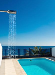 a swimming pool with a shower with the ocean in the background at FRONTLINE VILLA 26, Modern Coastal Design with Amazing Views in Puerto Calero