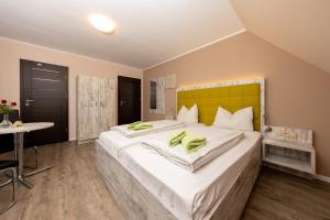 a bedroom with a large white bed with a yellow headboard at Hotel Ehlers in Schneverdingen