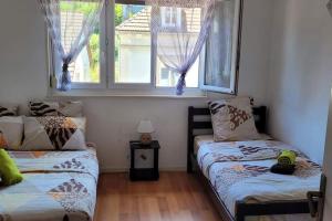 dwa łóżka w pokoju z dwoma oknami w obiekcie Bel appartement 6 personnes proche La Bresse w mieście Cornimont