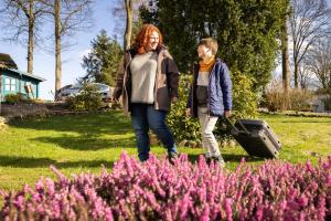 シュネーヴァーディンゲンにあるHotel Ehlersのピンクの花の咲く庭園を歩く二人の女性