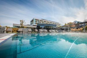 a swimming pool with chairs and a building at Hotel Lebensquell Bad Zell in Bad Zell