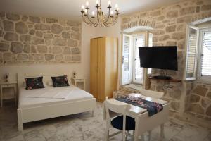 Schlafzimmer mit einem Bett, einem Tisch und einem TV in der Unterkunft Guesthouse Žmukić in Perast