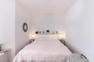 a white bedroom with a bed and two night stands at Am Horumertief in Wangerland