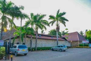 two cars parked in front of a building with palm trees at Best Western Jangwani Sea Breeze Resort in Dar es Salaam