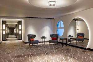 una sala d'attesa con sedie, tavoli e una finestra di Basel Marriott Hotel a Basilea
