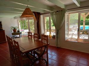 comedor con mesa de madera, sillas y ventanas en Gîtes Lalaurie, en Sauveterre-la-Lémance