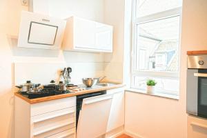 een keuken met witte kasten, een wastafel en een raam bij 50qm Apartment in Krefeld zentral gelegen mit hohen Decken - BEUYS Apartments - Krefeld in Krefeld