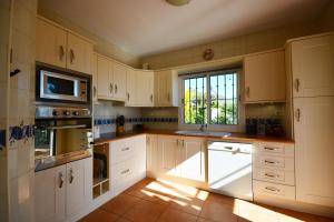 a large kitchen with white cabinets and a window at Casa Amarilla, Frigiliana Luxury Country villa with pool and parking HansOnHoliday Rentals in Frigiliana +27 photos