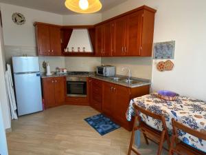 a kitchen with a table and a white refrigerator at La Porta sul Lungomare in Castelsardo