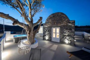 a patio with a tree and a white door at Red beach Harmony Suites Stone house in Akrotiri