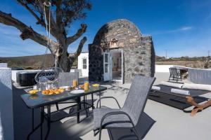a patio with a table and chairs and a tree at Red beach Harmony Suites Stone house in Akrotiri