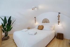 a bedroom with a white bed with towels on it at Red beach Harmony Suites Stone house in Akrotiri
