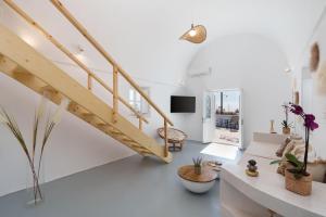 a white living room with a wooden staircase at Red beach Harmony Suites Stone house in Akrotiri