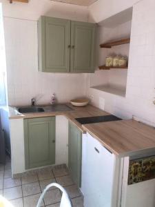 eine Küche mit grünen Schränken und einem Waschbecken in der Unterkunft Petite maison entre mer et campagne in Les Pieux