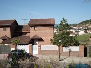Collado Mediano的住宿－Casa con jardín, 1 habitación, barbacoa，前面有停车位的砖房
