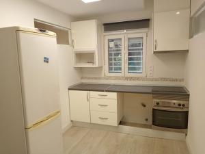 a kitchen with white cabinets and a white refrigerator at Casa con jardín, 1 habitación, barbacoa in Collado Mediano