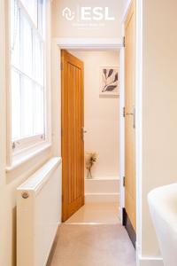a bathroom with a wooden door and a bath tub at Super Central - Quiet - 2 Bedroom Cottage in Shrewsbury