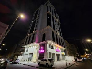 un grand bâtiment blanc avec un panneau violet dessus dans l'établissement فندق رواء العزيزية, à La Mecque