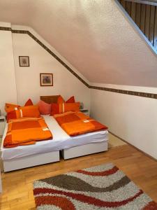 a bedroom with two beds with orange sheets and a rug at Györe Vendégház Galambok in Galambok