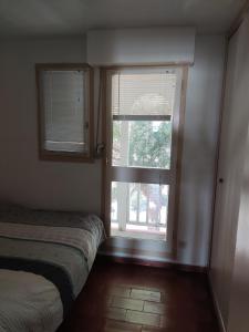 een slaapkamer met een bed en 2 ramen met jaloezieën bij T2C sympa vue splendide in Le Barcarès