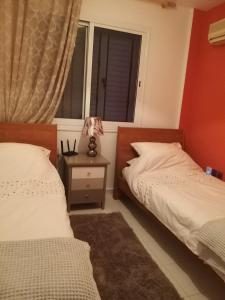 1 dormitorio con 2 camas y mesa con lámpara en Tala Gardens Apartment en Tala