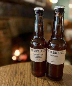 dos botellas de cerveza sentadas en una mesa de madera en The New Inn Heckfield, en Hook