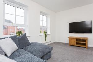 ein Wohnzimmer mit einem Sofa und einem Flachbild-TV in der Unterkunft Main Street Town House in Leyland