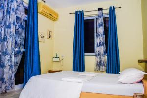 2 camas en una habitación con cortinas azules en Dona Rosa Holiday Apartment, en Varca