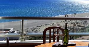 a bottle of wine sitting on a table next to the ocean at Appartement de vacances - Splendide vue sur mer, Parking privé in Le Barcarès