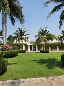 a lawn with palm trees and a building at The Palm Villa Jomtien C7 in Jomtien Beach