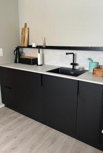 eine Küche mit schwarzen Schränken und einem Waschbecken in der Unterkunft Lofoten Kabelvåg-small apartment in Kabelvåg