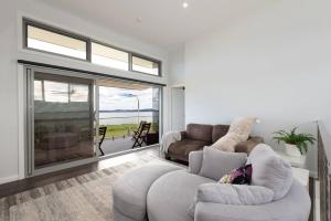 ein Wohnzimmer mit 2 Sofas und einem Sofa in der Unterkunft Absolute Waterfront, Amazing Views, Maloneys Beach in Maloney's Beach