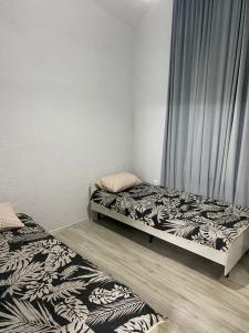 1 dormitorio con 2 camas y cortina en Коттедж в ЦО Париж-2, en Chok-Tal