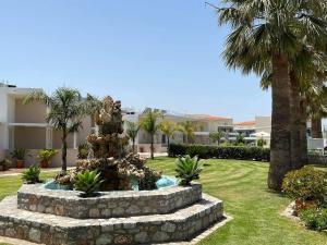 einen Brunnen inmitten eines Gartens mit Palmen in der Unterkunft Argiri Apartments & Suites in Georgioupoli