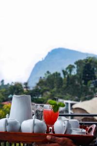 City Heaven Ella في إيلا: طاولة مع مشروب في كأس النبيذ مع الجبل