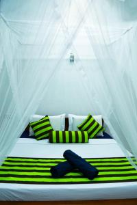 a bed with green and white striped sheets and pillows at City Heaven Ella in Ella