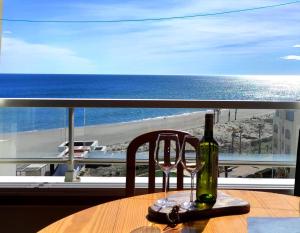 a bottle of wine sitting on a table with a view of the ocean at Appartement de vacances - Splendide vue sur mer, Parking privé in Le Barcarès