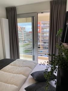 een slaapkamer met een bed en een groot raam bij Petit plage Nieuwpoort-Bad in Nieuwpoort